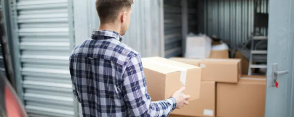 Client inspectant un box de stockage ouvert dans le couloir d'une installation de garde-meuble à Valenciennes